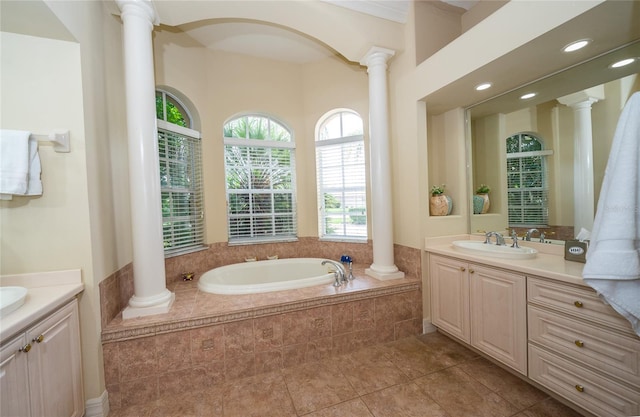 bathroom featuring tiled bath, tile patterned floors, vanity, and ornate columns