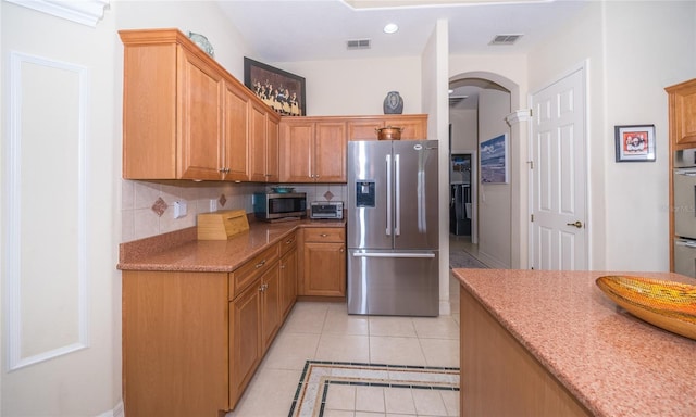 kitchen with light tile patterned floors, stainless steel appliances, and decorative backsplash