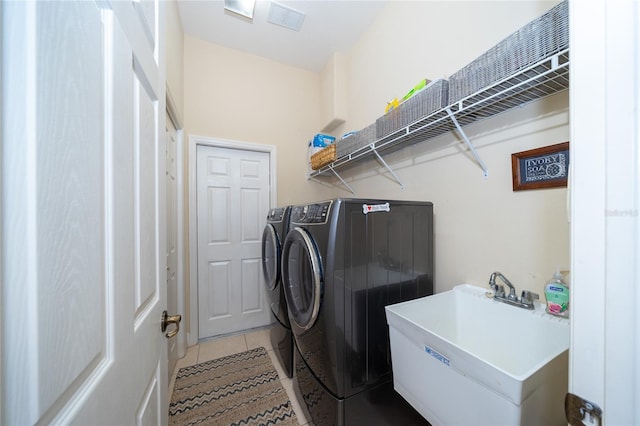 laundry area featuring washing machine and dryer, light tile patterned flooring, and sink