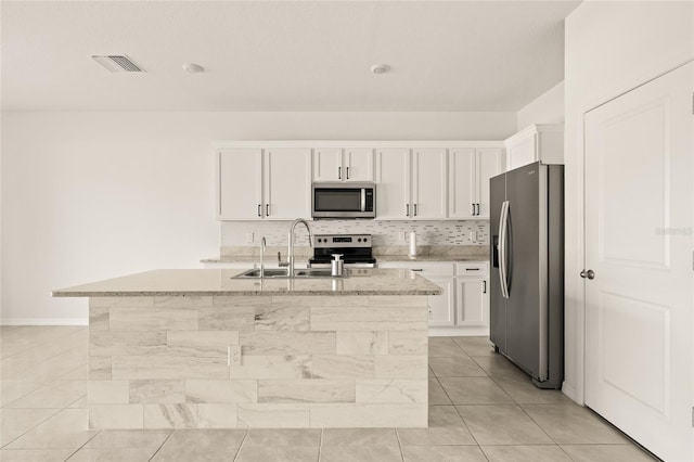 kitchen featuring an island with sink, white cabinets, light tile patterned flooring, and stainless steel appliances