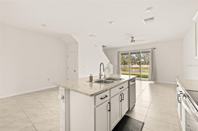 kitchen with light stone countertops, appliances with stainless steel finishes, white cabinetry, sink, and a center island with sink