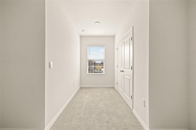 corridor featuring light carpet and a textured ceiling