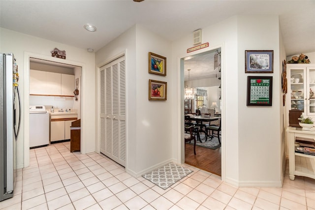 7312 7th Ave NW, Bradenton, FL 34209 - corridor featuring washer / clothes dryer, a chandelier, light tile patterned floors, and baseboards
