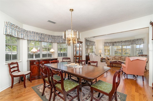 7312 7th Ave NW, Bradenton, FL 34209 - dining room featuring light wood-style floors, a chandelier, and a textured ceiling