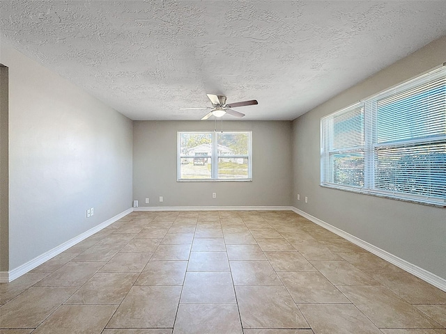 tiled spare room with a textured ceiling, ceiling fan, and plenty of natural light