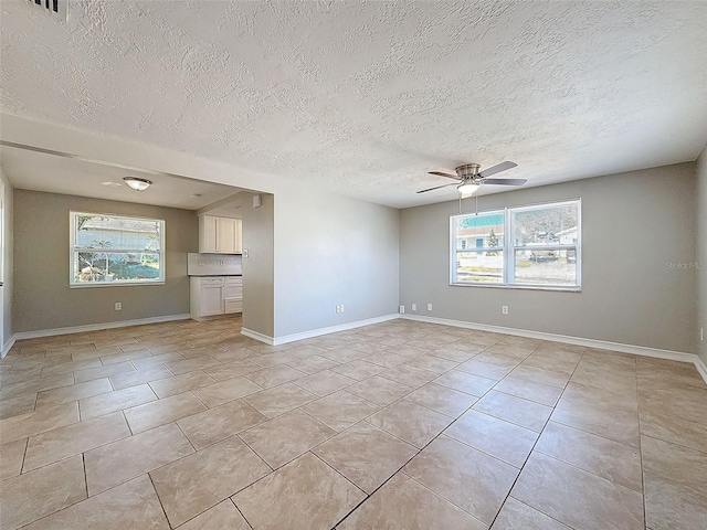 spare room with ceiling fan, light tile patterned floors, and a textured ceiling