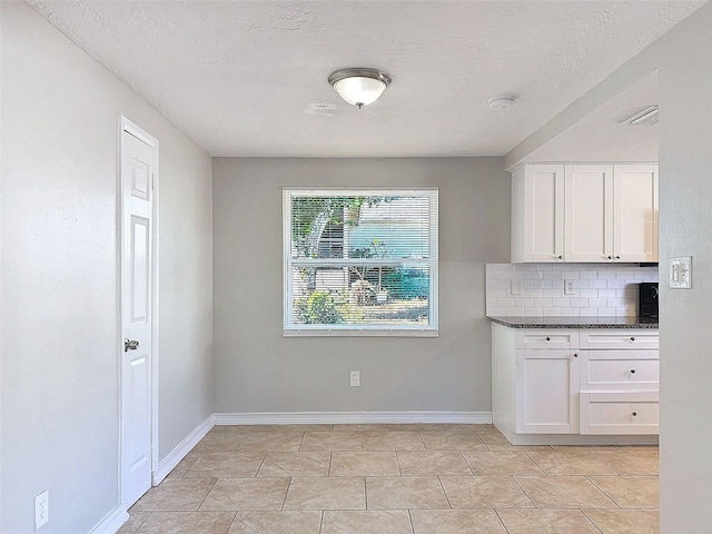 kitchen with backsplash, white cabinetry, and a textured ceiling