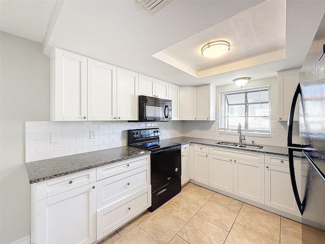 kitchen featuring black appliances, white cabinets, light tile patterned flooring, and a raised ceiling