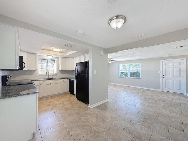 kitchen with white cabinets, black appliances, tasteful backsplash, sink, and a raised ceiling