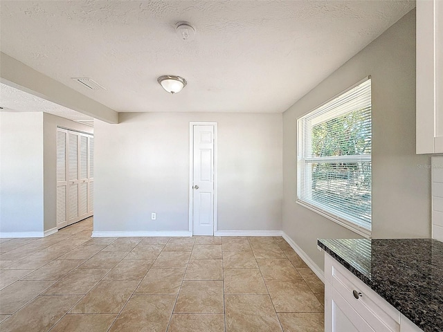 unfurnished room featuring a textured ceiling and light tile patterned floors