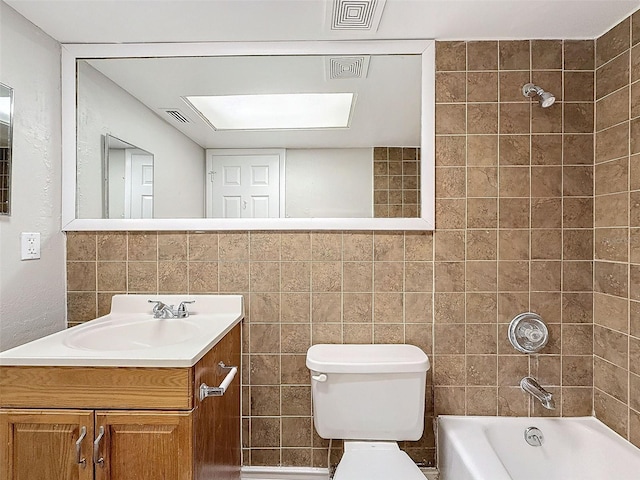 full bathroom with toilet, vanity, tile walls, and tiled shower / bath combo