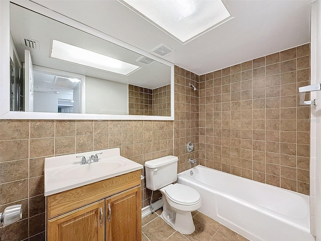 full bathroom with tiled shower / bath combo, tile patterned floors, vanity, tile walls, and toilet