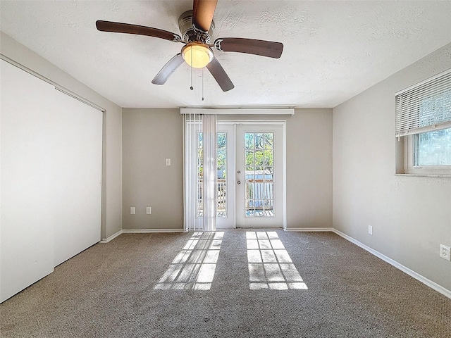 carpeted spare room featuring a textured ceiling, ceiling fan, and french doors