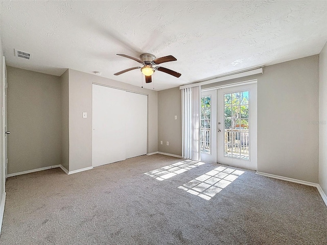 empty room with carpet, french doors, a textured ceiling, and ceiling fan