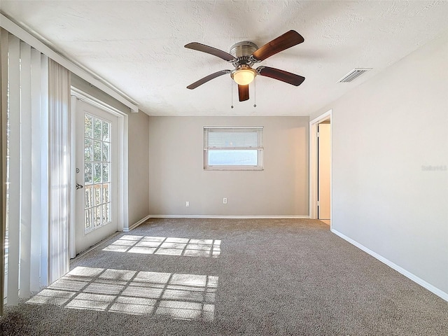 carpeted spare room featuring ceiling fan and a textured ceiling