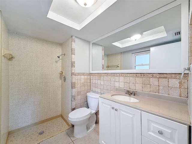 bathroom featuring tile patterned floors, vanity, tile walls, toilet, and tiled shower