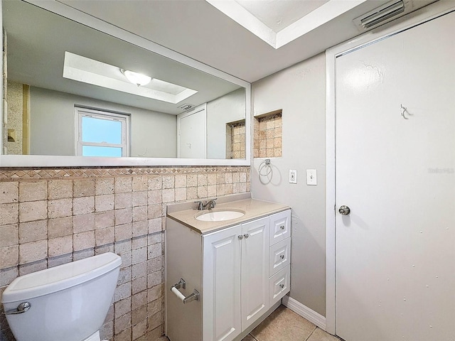 bathroom featuring tile patterned floors, tile walls, toilet, and vanity