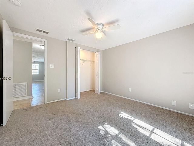 unfurnished bedroom featuring light carpet, ceiling fan, a textured ceiling, and a closet