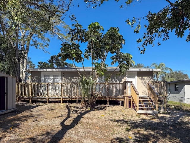 back of property with a wooden deck and a shed