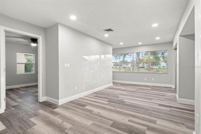 empty room featuring plenty of natural light, ceiling fan, and light hardwood / wood-style flooring