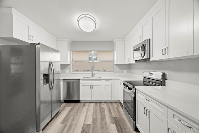 kitchen featuring white cabinetry, appliances with stainless steel finishes, sink, and light hardwood / wood-style flooring