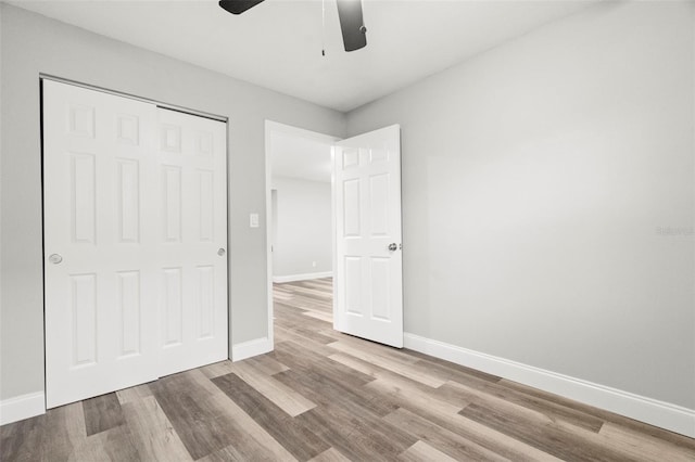 unfurnished bedroom featuring ceiling fan, a closet, and light hardwood / wood-style flooring