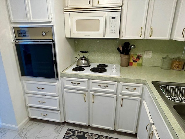 kitchen featuring sink, white appliances, and white cabinetry