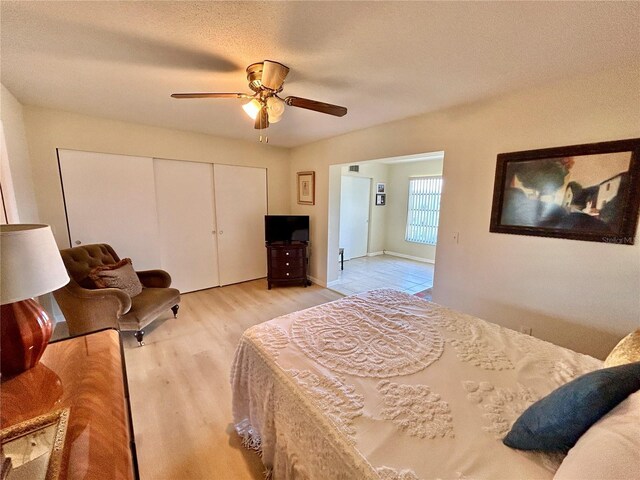 bedroom with ceiling fan, a textured ceiling, a closet, and light wood-type flooring