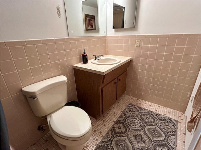 bathroom featuring toilet, vanity, tile walls, and tile patterned flooring