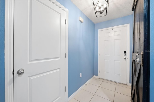 doorway with a textured ceiling and light tile patterned flooring