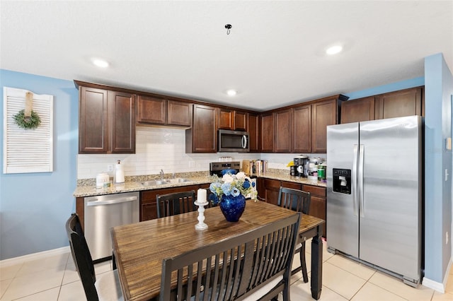 kitchen featuring light tile patterned floors, sink, light stone counters, and stainless steel appliances