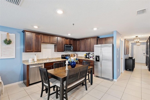 kitchen with tasteful backsplash, sink, stainless steel appliances, light tile patterned floors, and dark brown cabinets