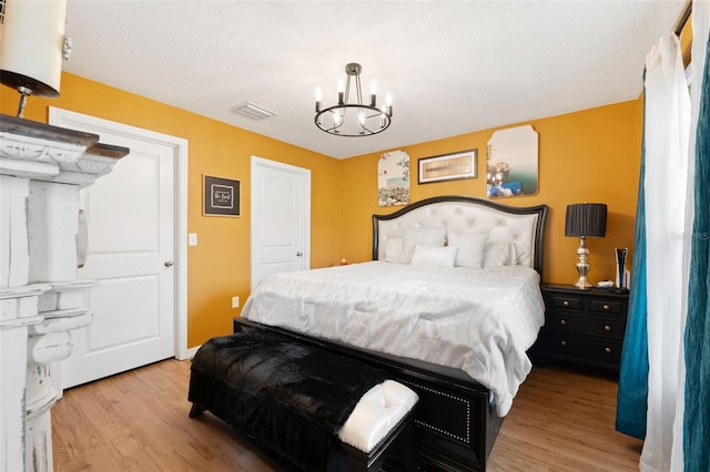 bedroom featuring a notable chandelier, a textured ceiling, and light hardwood / wood-style floors