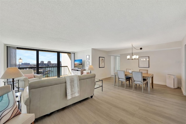 living room with a textured ceiling, a notable chandelier, baseboards, light wood-type flooring, and floor to ceiling windows