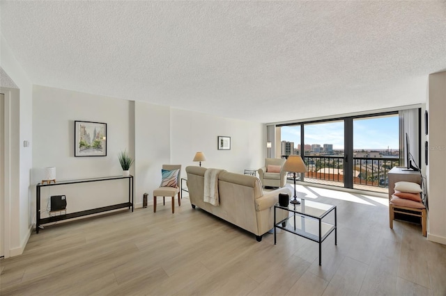 living room with light wood-style floors, floor to ceiling windows, a textured ceiling, and baseboards