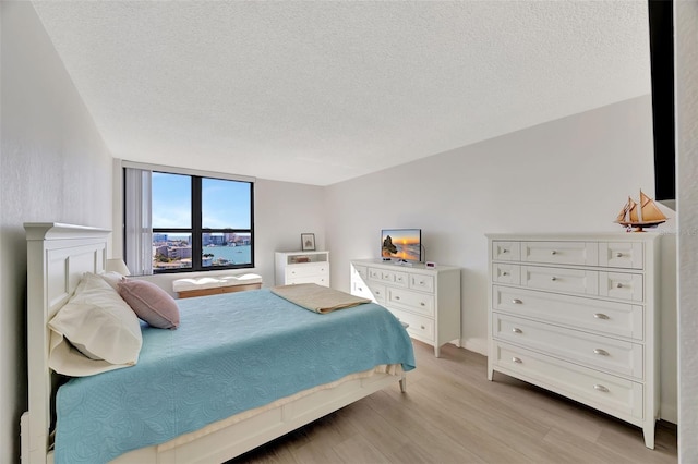 bedroom with light wood-style floors and a textured ceiling