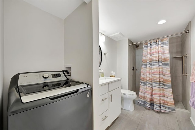 bathroom featuring washer / dryer, tiled shower, vanity, and toilet