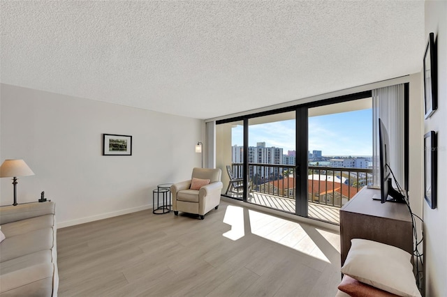 interior space featuring baseboards, floor to ceiling windows, a textured ceiling, and light wood finished floors