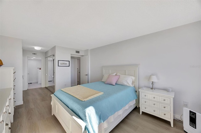 bedroom featuring a closet, visible vents, and wood finished floors