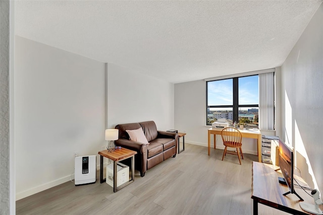 interior space with light wood finished floors, baseboards, and a textured ceiling