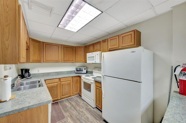 kitchen featuring white appliances, a sink, visible vents, light wood-style floors, and light countertops