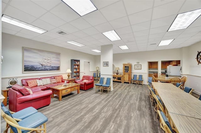 living room featuring visible vents, a drop ceiling, and wood finished floors