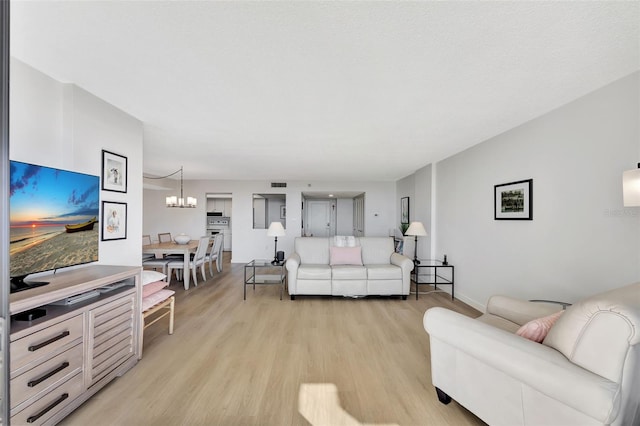 living area featuring light wood-style floors, a chandelier, and visible vents