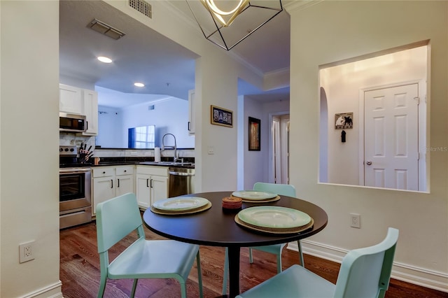 dining room with dark hardwood / wood-style flooring, sink, and ornamental molding