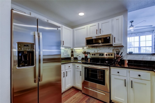 kitchen with white cabinetry, appliances with stainless steel finishes, dark stone countertops, and decorative backsplash