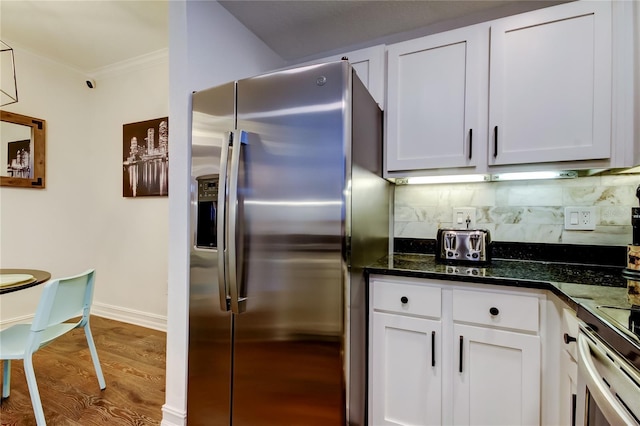 kitchen featuring white cabinetry, stainless steel fridge with ice dispenser, crown molding, and dark stone countertops