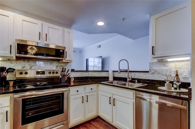 kitchen featuring dark stone countertops, sink, stainless steel appliances, and white cabinets