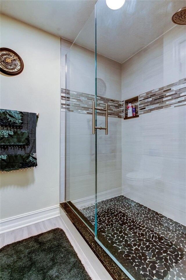 bathroom with hardwood / wood-style floors and a tile shower