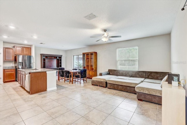 living room with ceiling fan, light tile patterned floors, plenty of natural light, and a textured ceiling