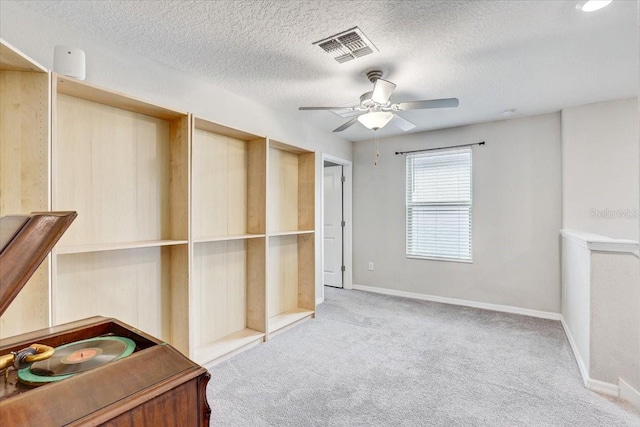 interior space featuring light carpet, a textured ceiling, and ceiling fan